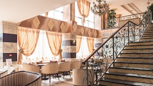 Un vestíbulo de hotel con una escalera, zona de estar y elementos decorativos.
