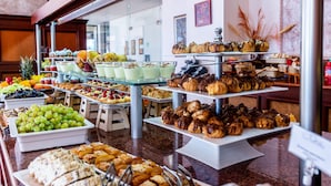 Un bufé con diversas opciones de comida, incluyendo frutas, pasteles y postres.