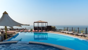 Una piscina con sillas de descanso y un pabellón, con vistas al mar.