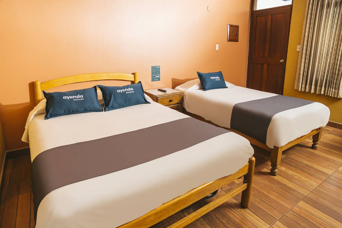 Habitación de hotel con dos camas, cada una con un almohadón que dice "avenda hotels".