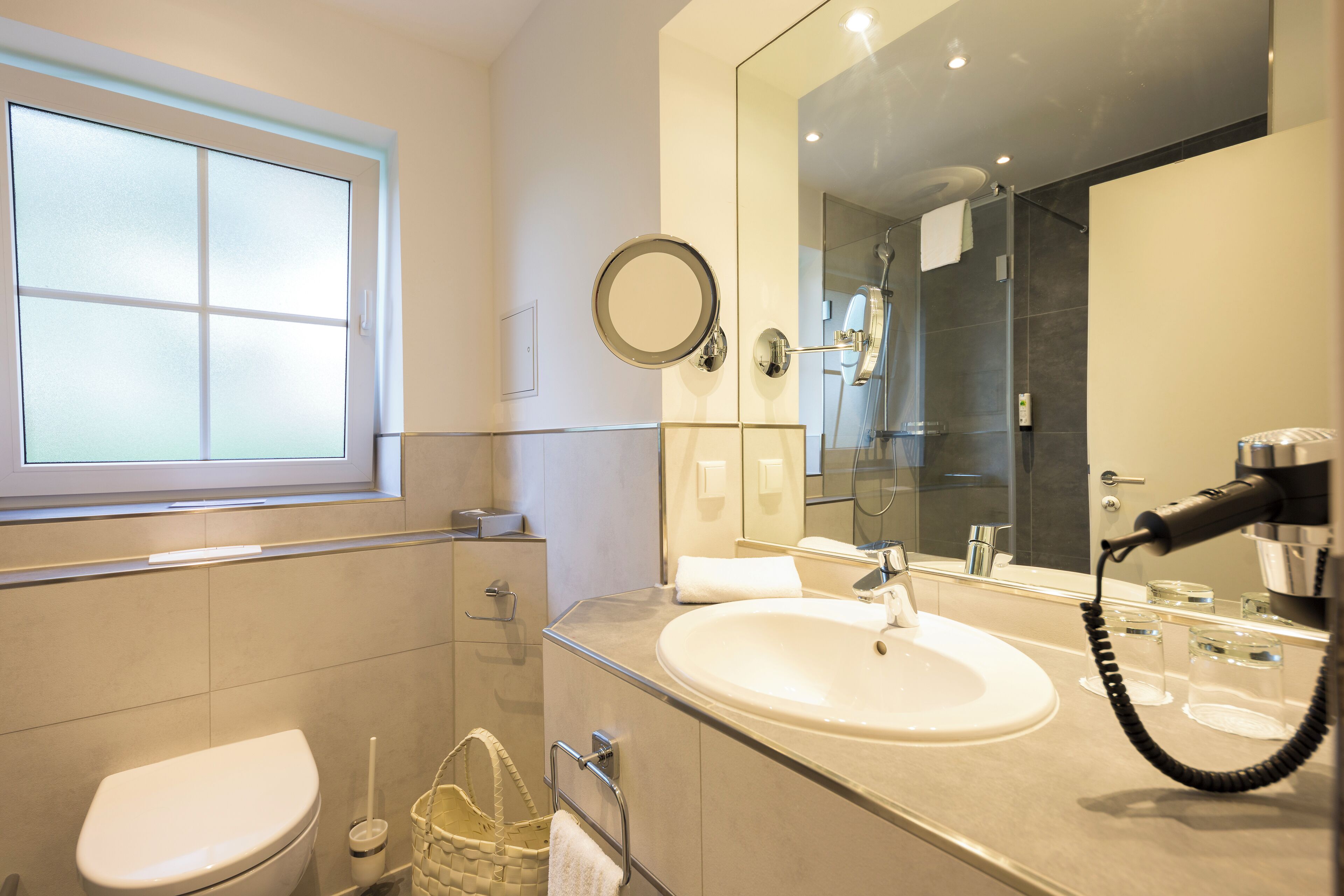 Une salle de bain moderne équipée de toilettes, d’un lavabo et d’un miroir.
