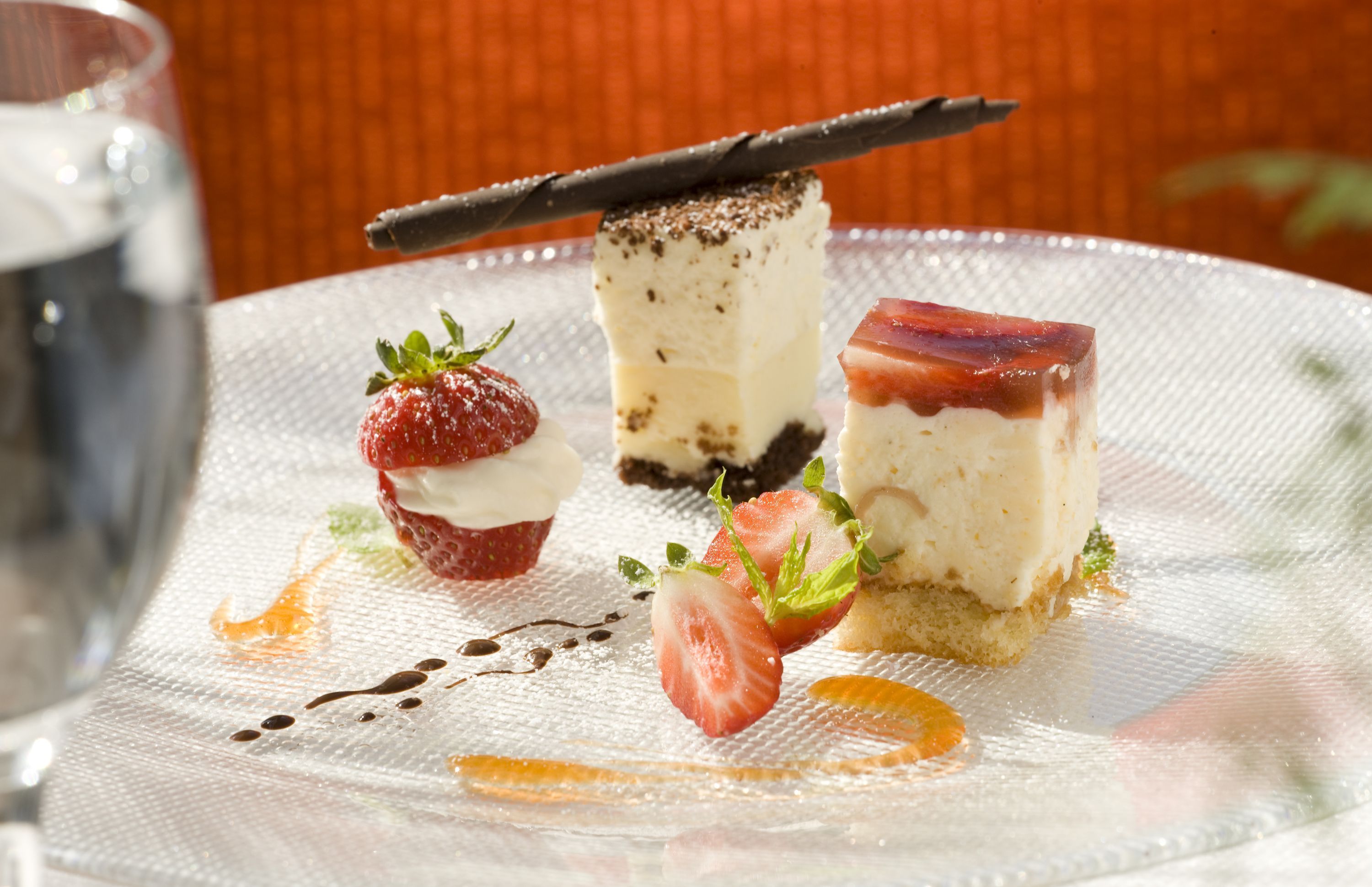 Desserteller mit Schokoladenstück, Erdbeeren und einem Kuchenstück auf einer strukturierten weißen Serviette.