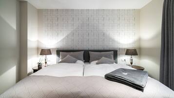 A neatly made bed with a patterned bedspread, two bedside lamps, and a headboard with a geometric pattern.