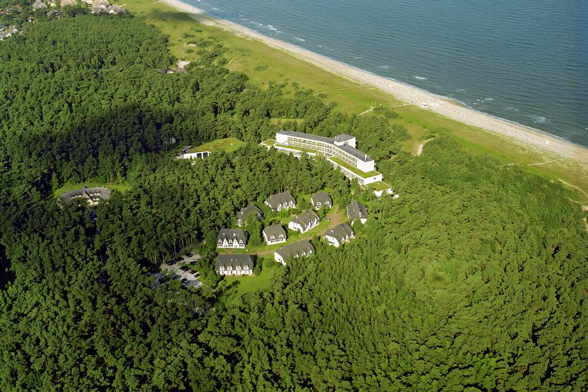 An aerial view of a resort with multiple buildings, a beach, and dense forest.
