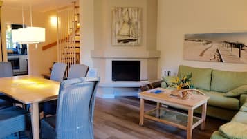 Una sala de estar moderna con comedor, chimenea y un cuadro de un velero.
