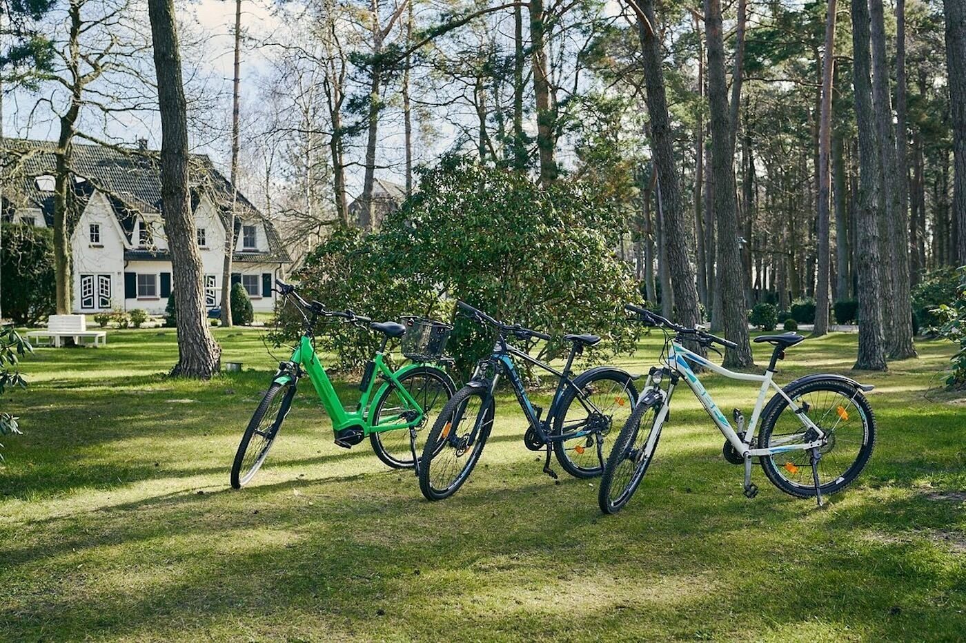 A row of bicycles parked on a grassy lawn with a house in the background.