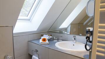 A modern bathroom with a skylight, a large mirror, and a sink.