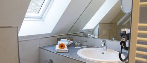 Une salle de bain moderne dotée d’une lucarne, d’un grand miroir et d’un lavabo.