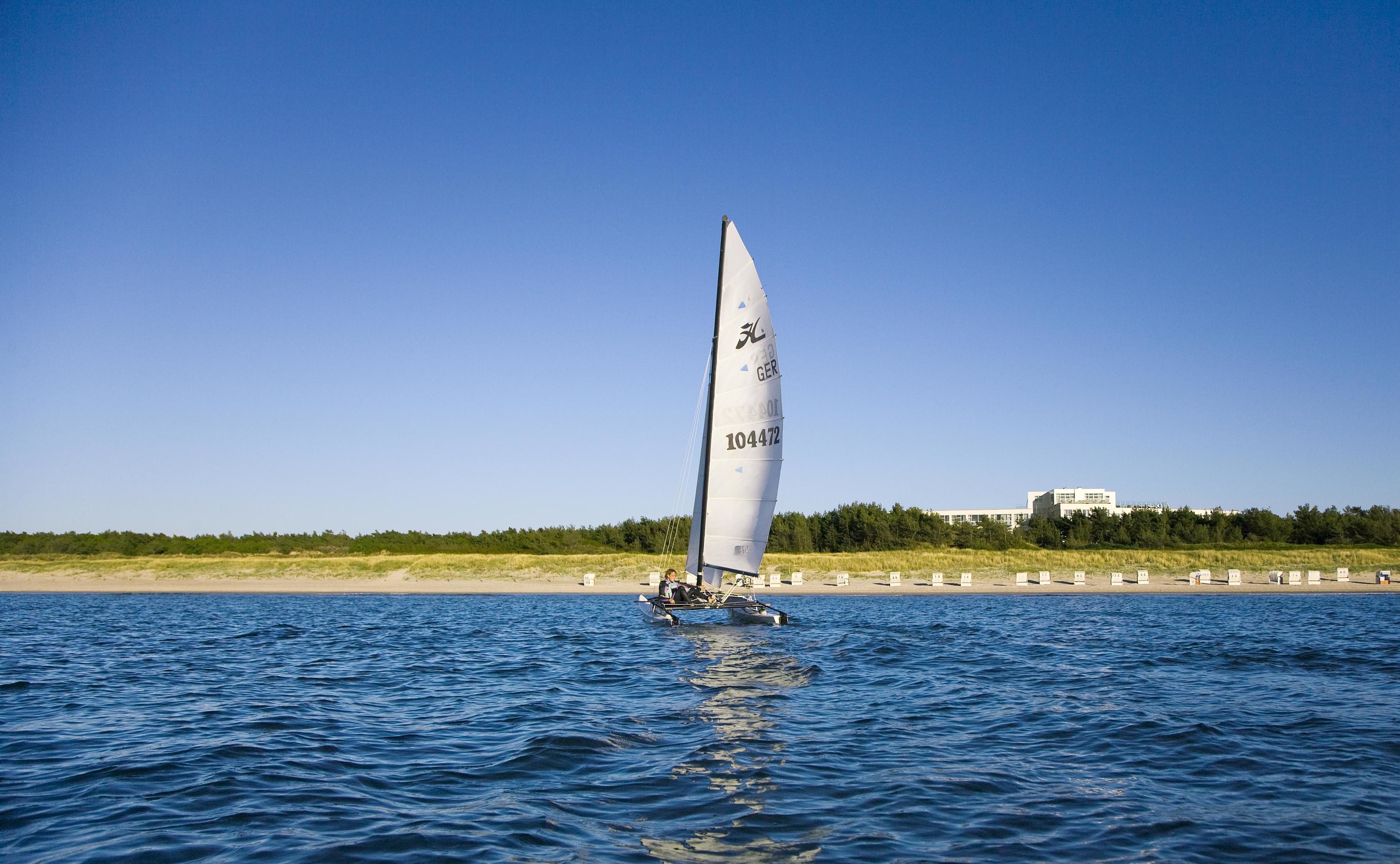 A sailboat on a body of water with a clear sky.