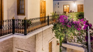 Une cour avec un balcon, des plantes en pot et une vue sur le ciel.