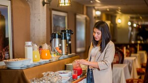 Un buffet proposant une variété d'aliments et de boissons, notamment un saladier de fruits, des céréales et un distributeur de jus.