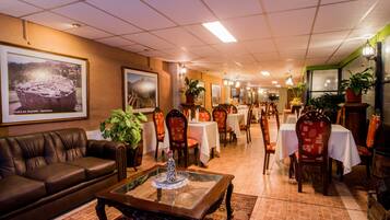 Un hall de hotel con un sofá de cuero, una mesa de centro y varias mesas de comedor con sillas.