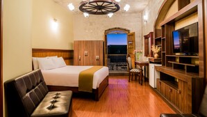 Une chambre d’hôtel avec un lit, un canapé, une télévision et un bureau.