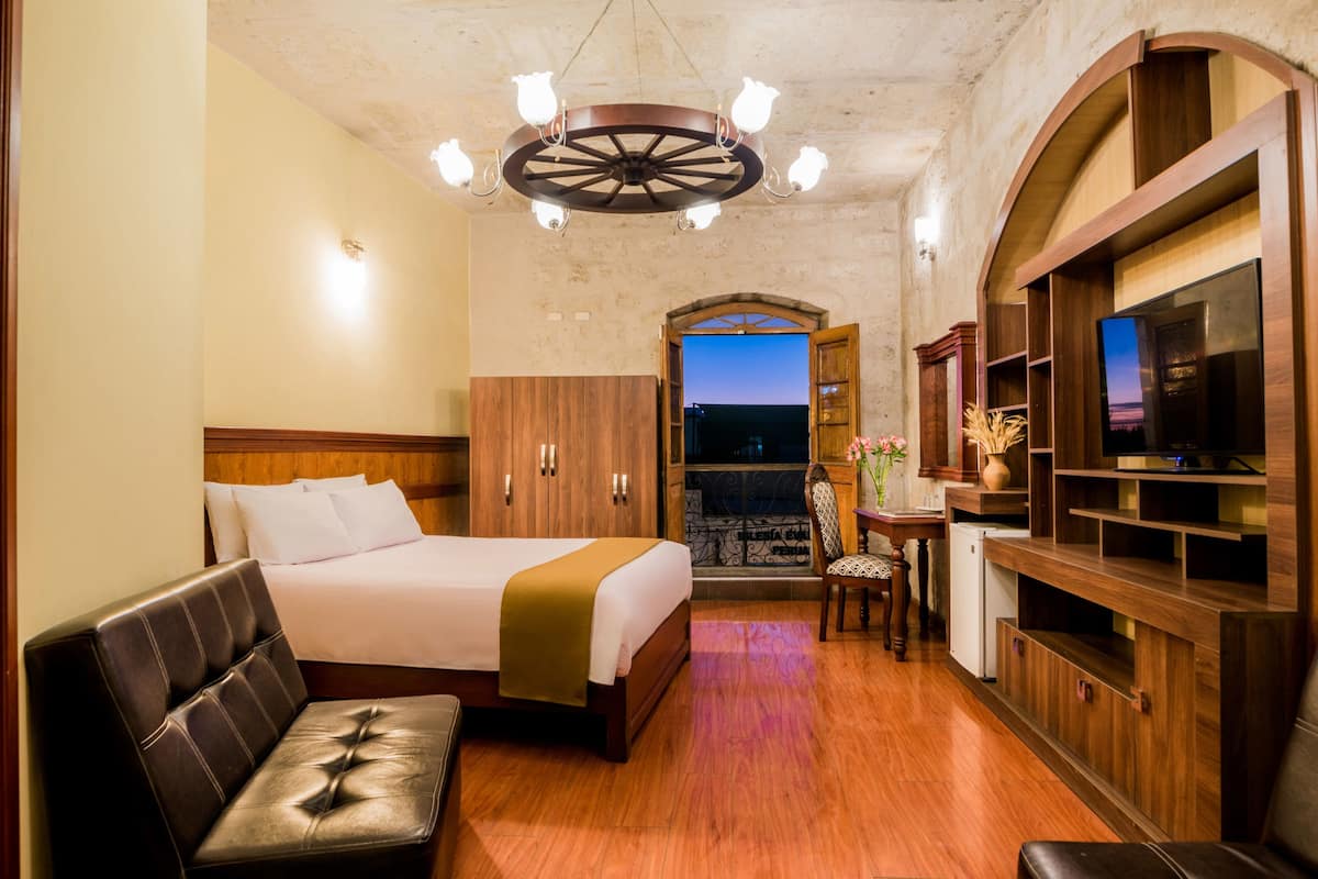 Una habitación de hotel con cama, sofá, televisor y escritorio.