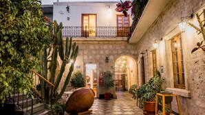 Une cour avec un sol en pierre, des plantes en pot, une grande cuve en bois et un escalier.