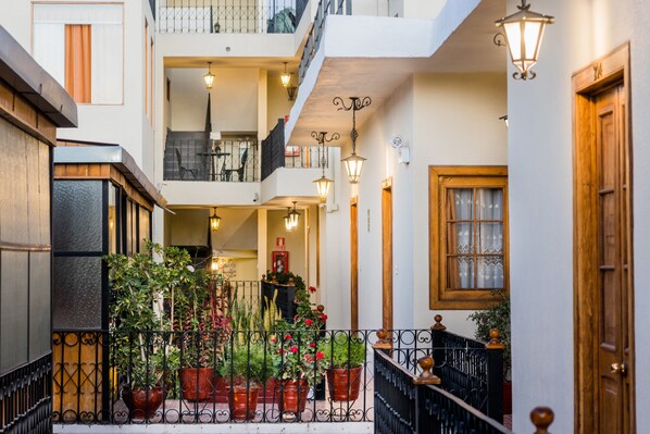 A multi-level courtyard with potted plants, a staircase, and a wooden door. - Majestad Boutique Hotel (Arequipa)