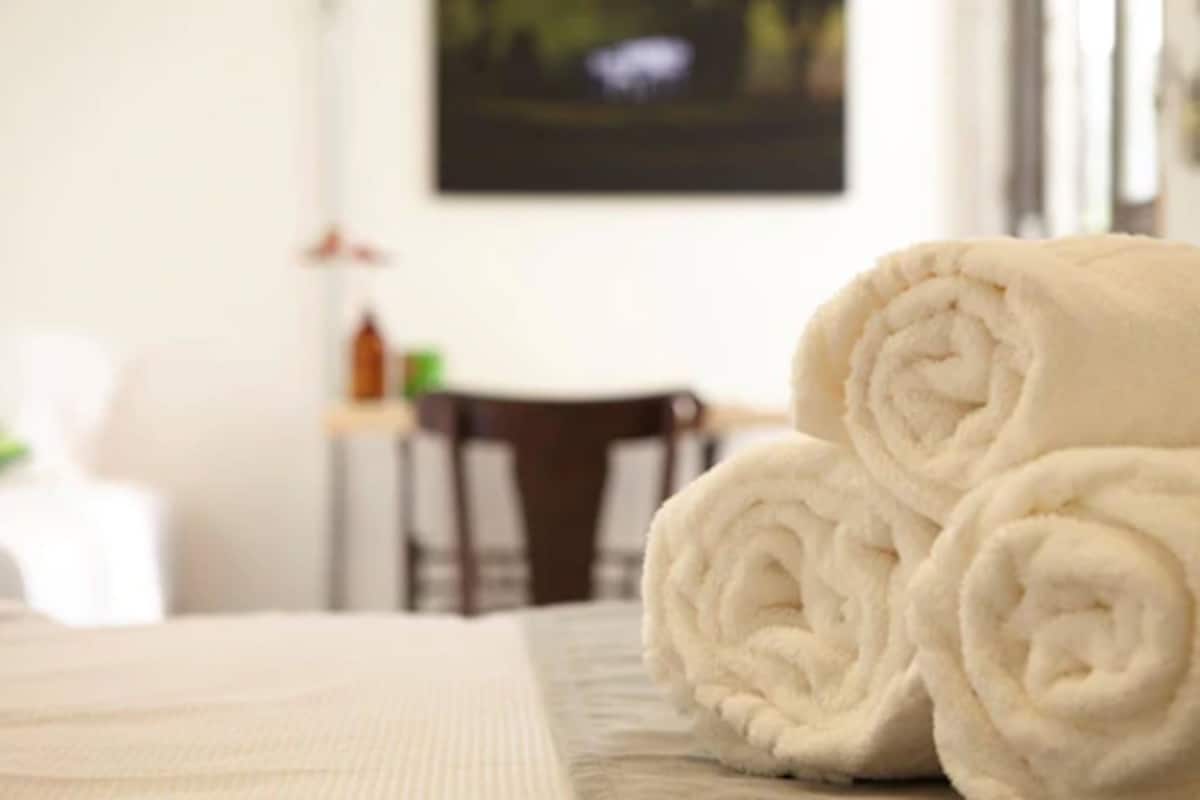 A neatly made bed with rolled white towels.