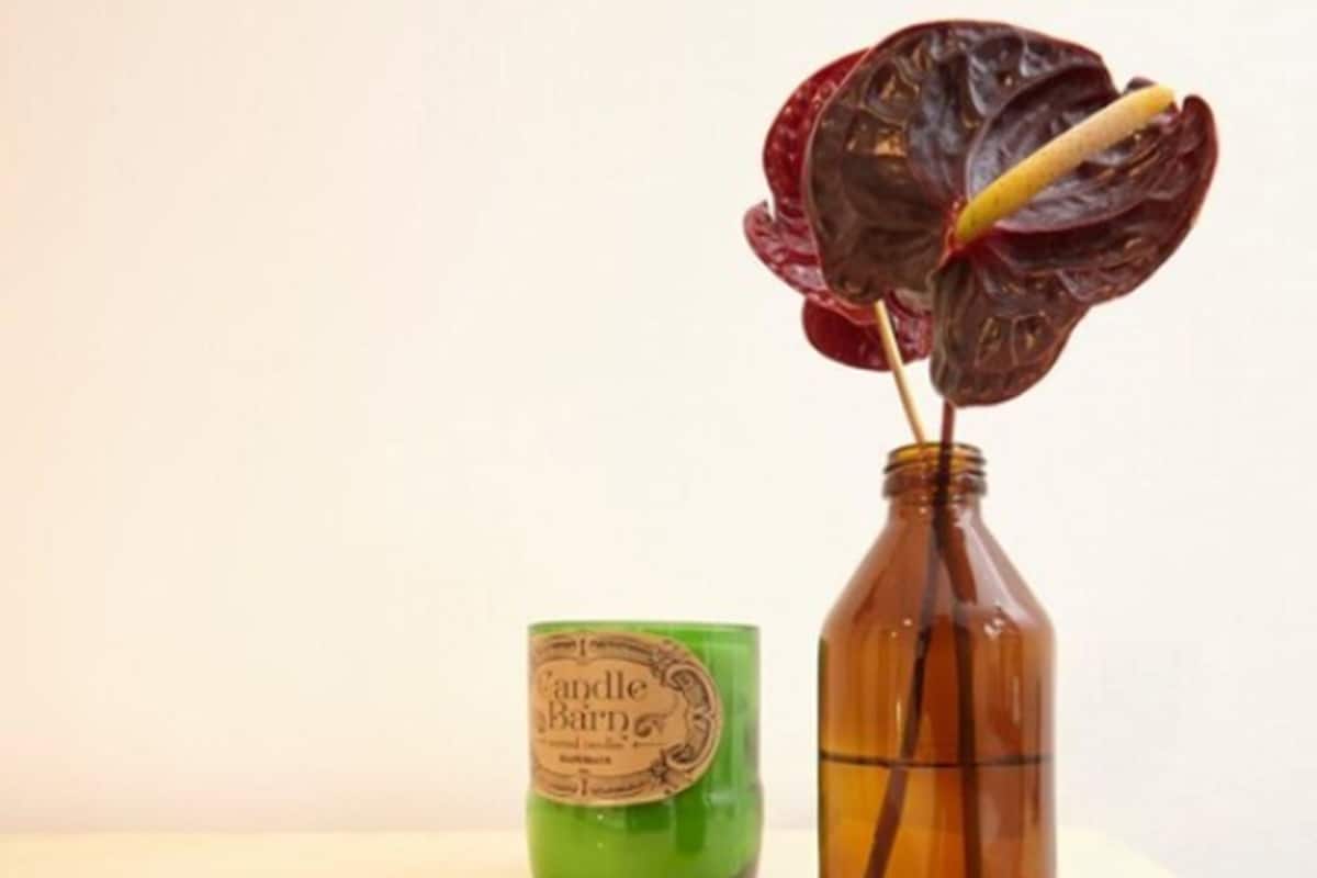 A candle in a brown bottle and a green candle in a green container.