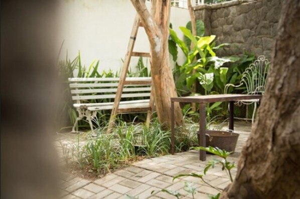 Une terrasse de jardin avec un banc en bois, une échelle et des plantes en pot.