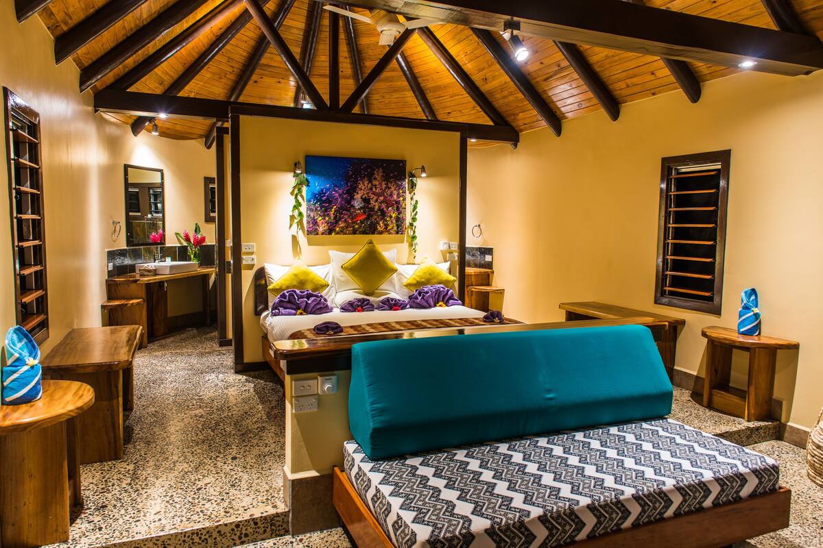 A hotel room with a bed, a desk, a chair, a small table, and a window.