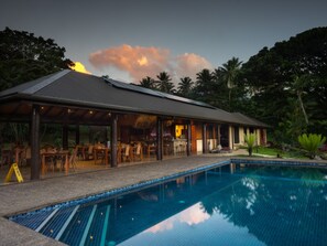 A poolside area with a covered seating area, a bar, and a pool.