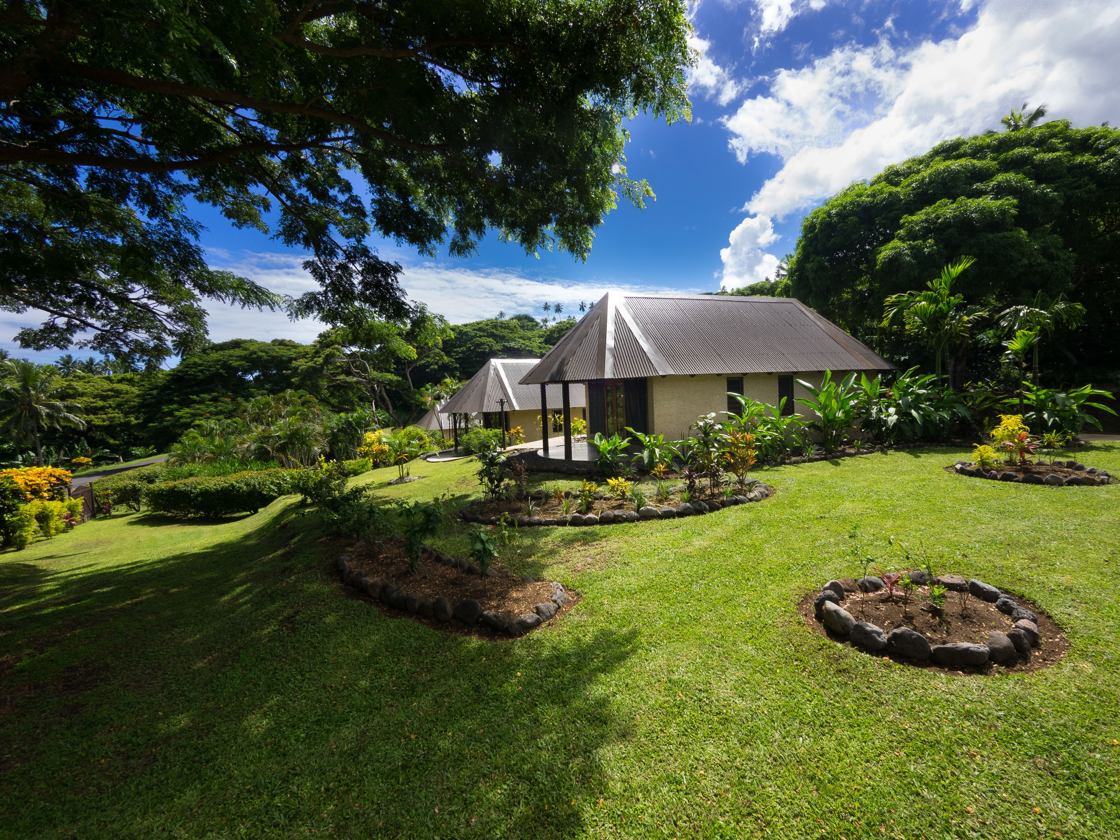 A building with a sloped roof surrounded by lush greenery and well-maintained lawns.