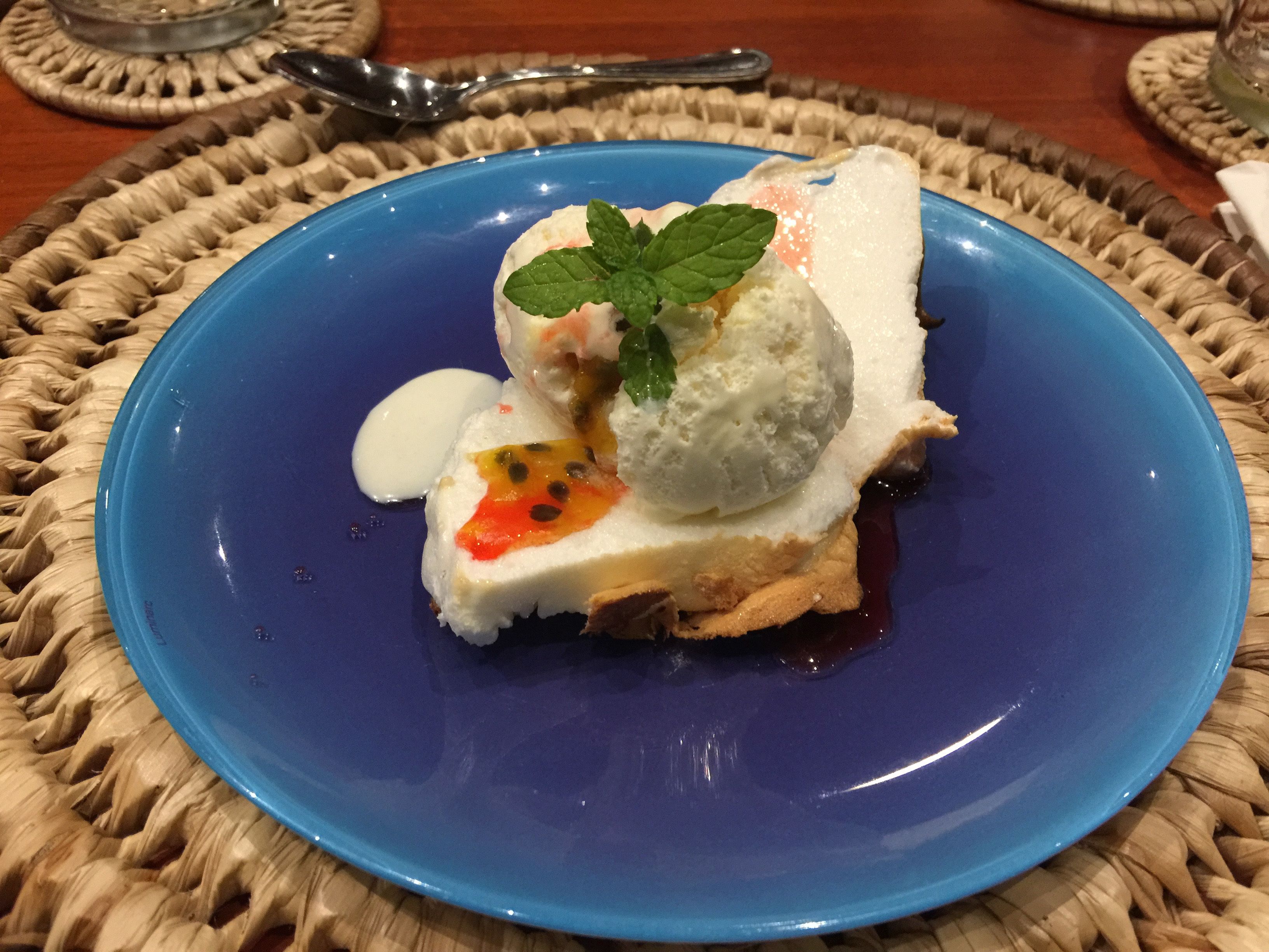 Un dessert servi dans une assiette bleue, posée sur un set de table en fibres tressées.