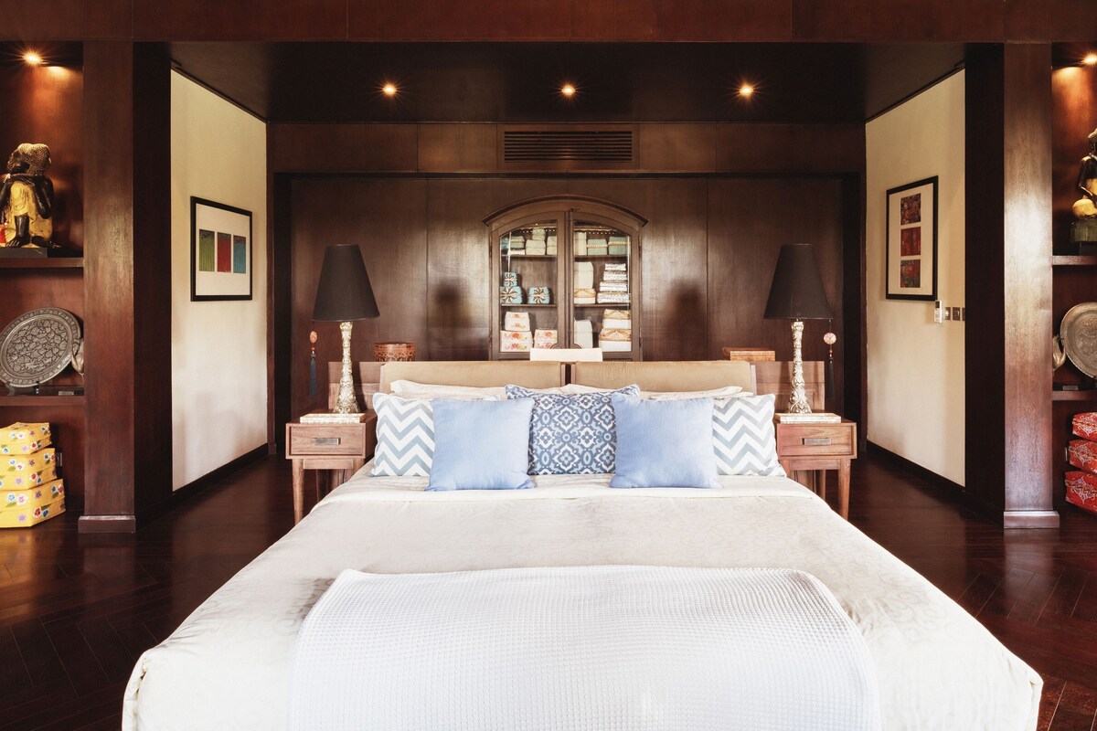 A bedroom with a large bed, two nightstands, a dresser, and a wardrobe.