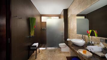 A modern bathroom with a large mirror, a sink, and a toilet. There is a towel rack and a shower area visible.