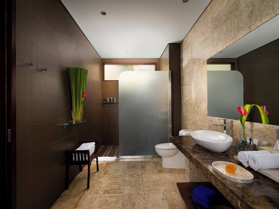 A modern bathroom with a large mirror, a sink, and a toilet. There is a towel rack and a shower area visible.