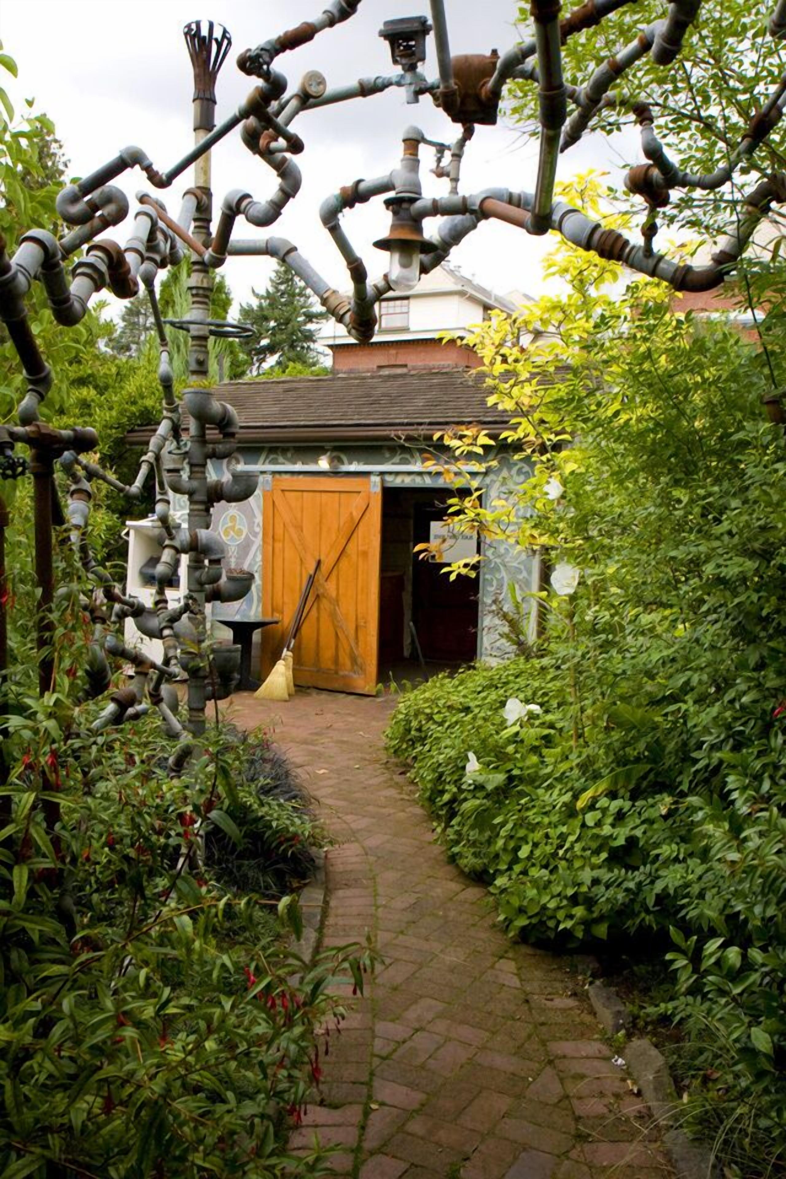 Un sendero de jardín que conduce a un edificio rústico con una puerta de madera y una chimenea.
