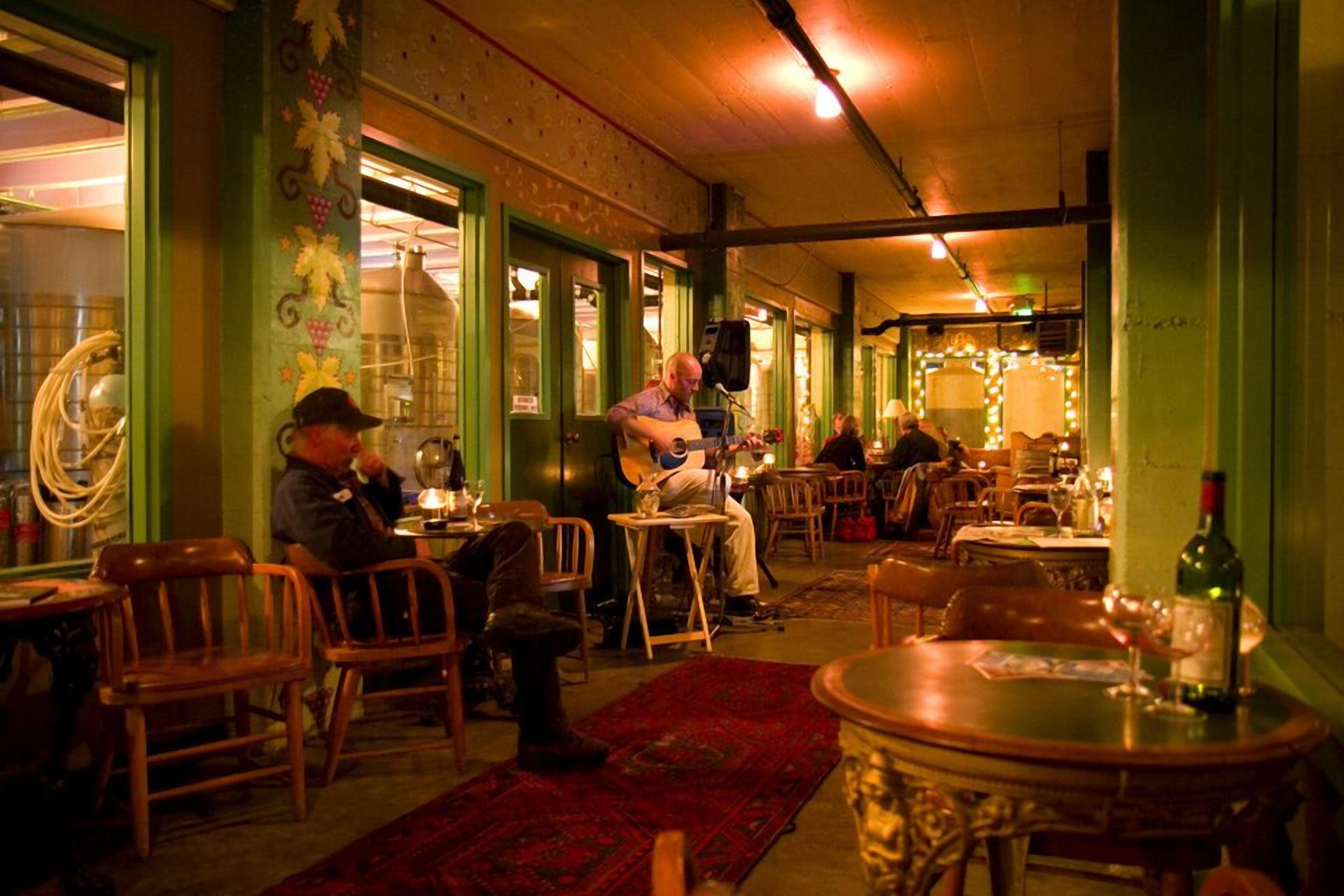 A restaurant with wooden chairs and tables, a red carpet, and a bottle of wine on a table.