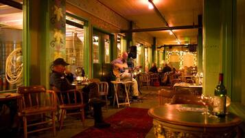 A restaurant with wooden chairs and tables, a red carpet, and a bottle of wine on a table.