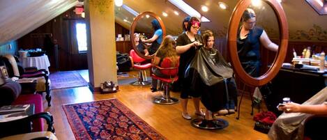 A salon with multiple hairdressing stations, a patterned carpet, and a wooden ceiling.