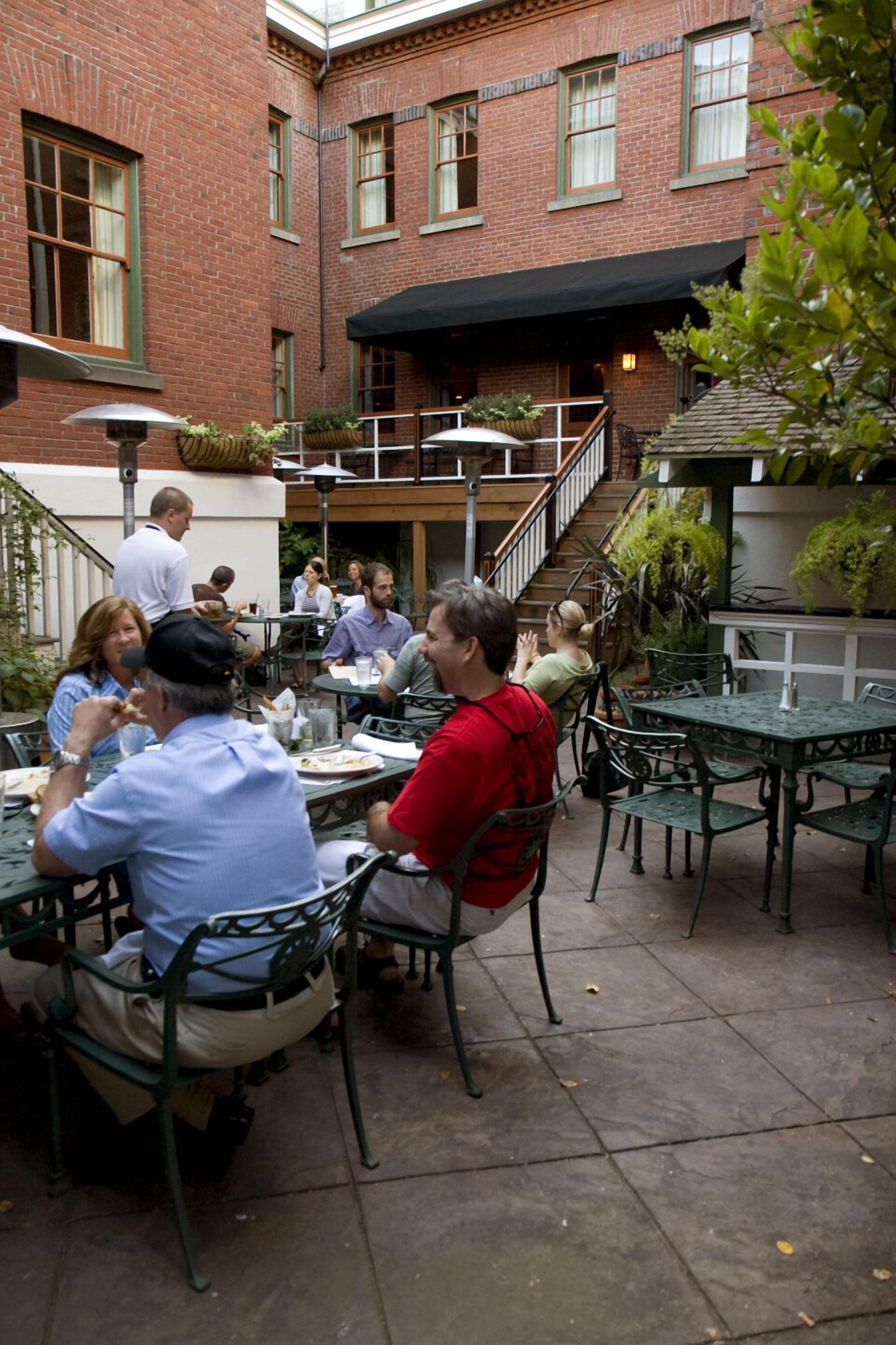 Un área de comedor al aire libre con paredes de ladrillo y sillas de metal verde.