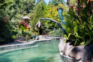 A clear pool with a stone edge, surrounded by lush greenery and a decorative metal structure. - McMenamins Edgefield (Troutdale)