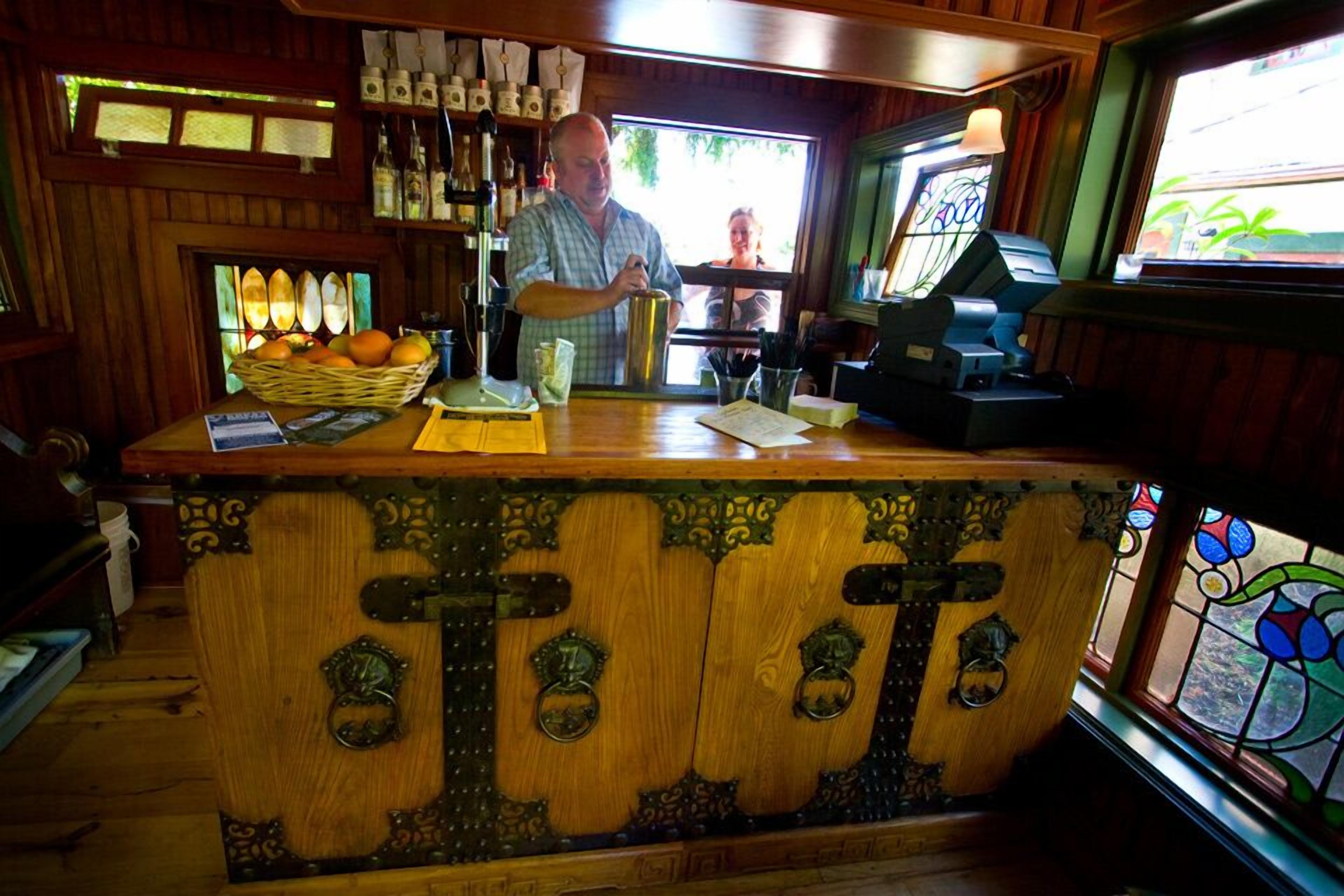 A bar area with a wooden counter, bottles, and a window with a view.