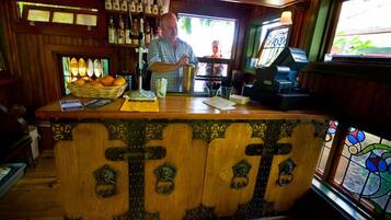 A bar area with a wooden counter, bottles, and a window with a view.