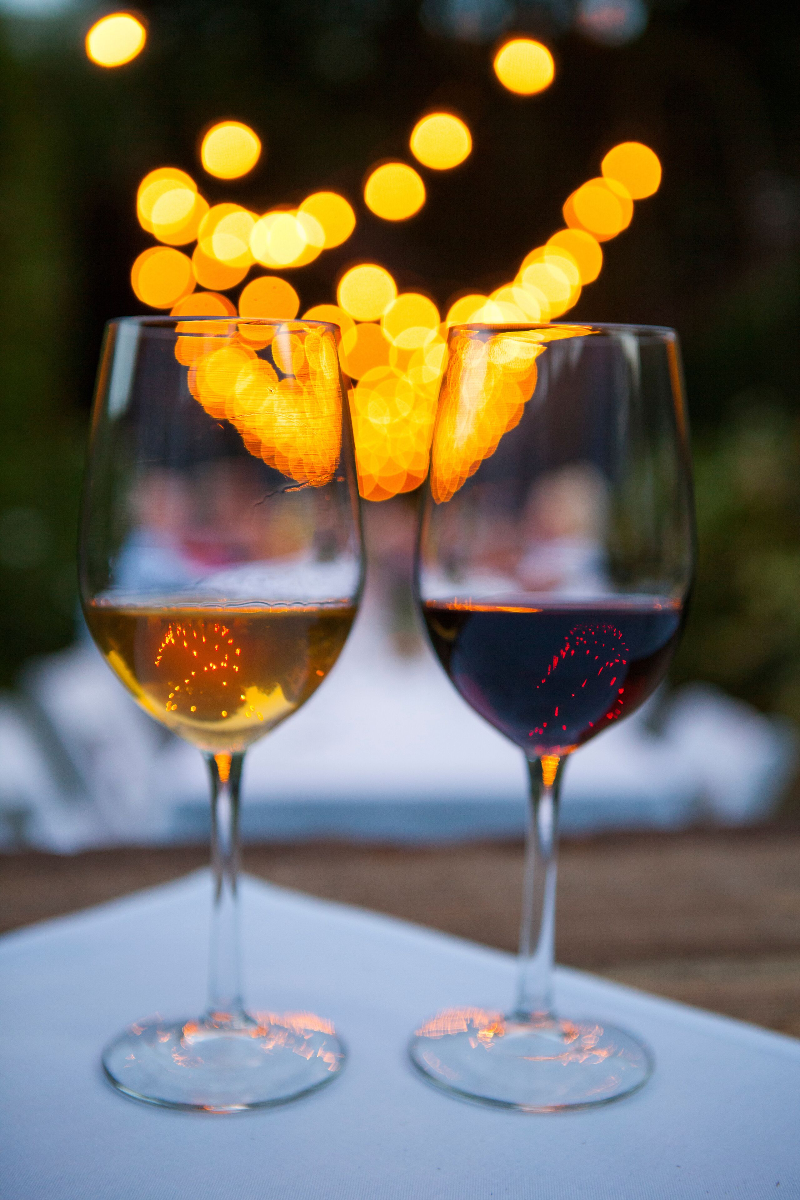 Dos copas de vino sobre una mesa, con un fondo borroso de luces.