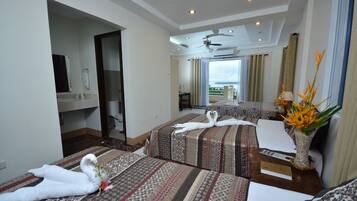 A hotel room with two beds, a ceiling fan, a view of the outdoors, and a vase with flowers on the nightstand.