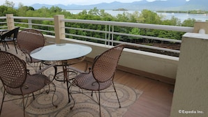 A balcony with a table and chairs, offering a view of a lake and mountains. - Villa de Sierra Vista (Puerto Princesa)