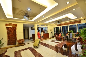 A lobby with a reception desk, seating area, and a large plant. - Villa de Sierra Vista (Puerto Princesa)