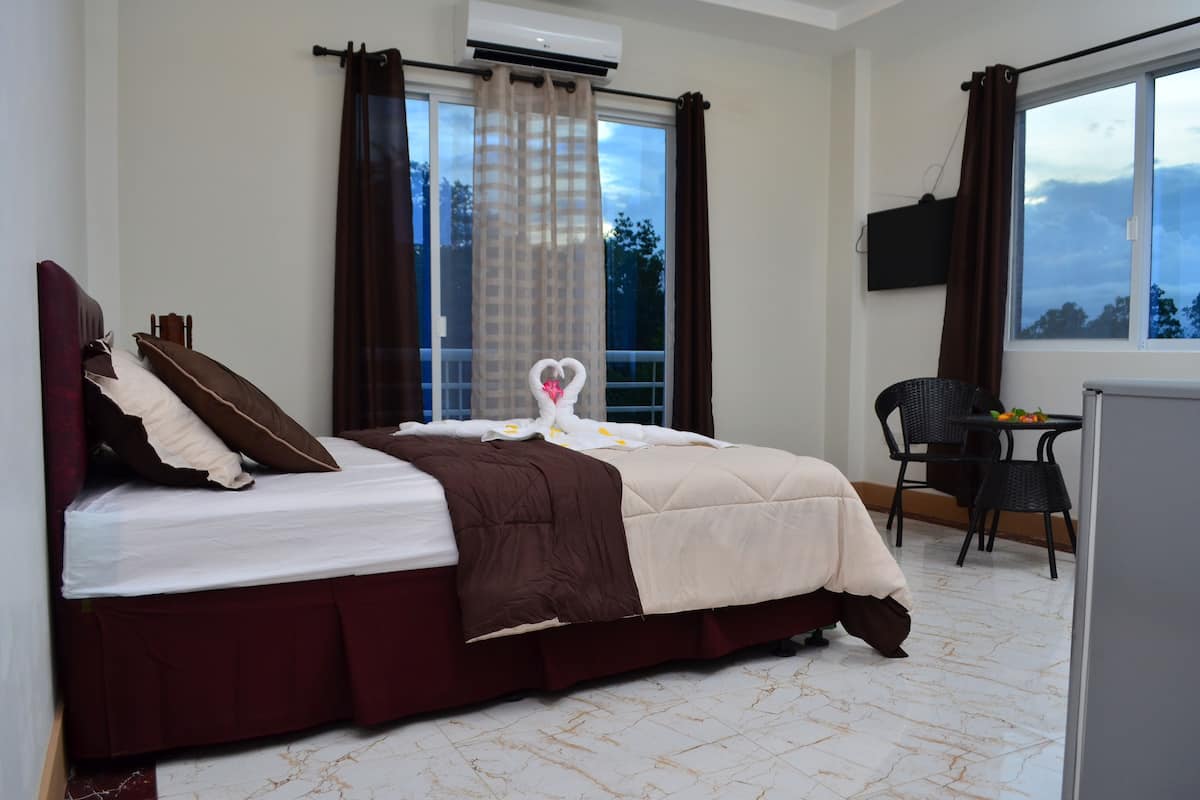 A hotel room with a bed, a desk, and a chair.