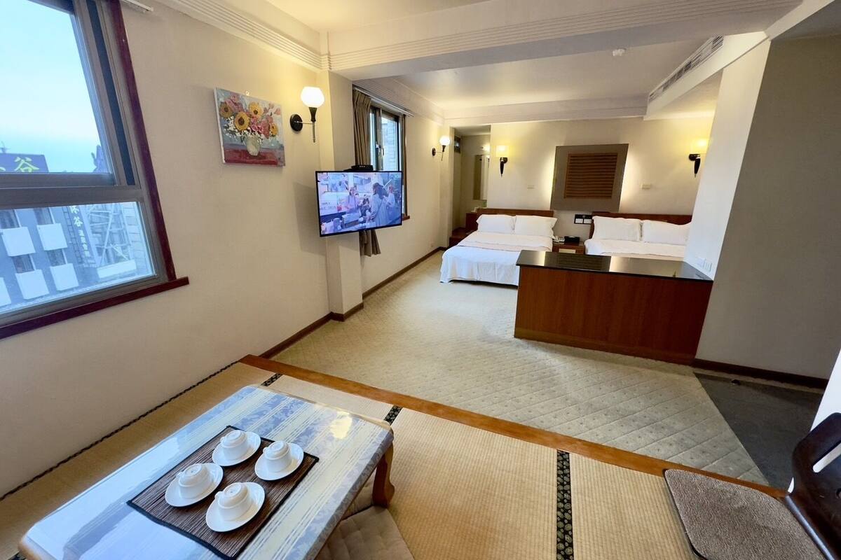 A hotel room with a TV, a dining table with plates, a bed, and a desk.