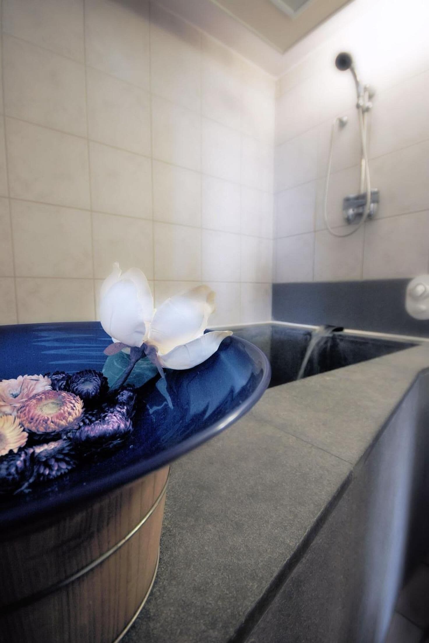Une salle de bain avec une baignoire, une douche et un lavabo bleu orné de fleurs.