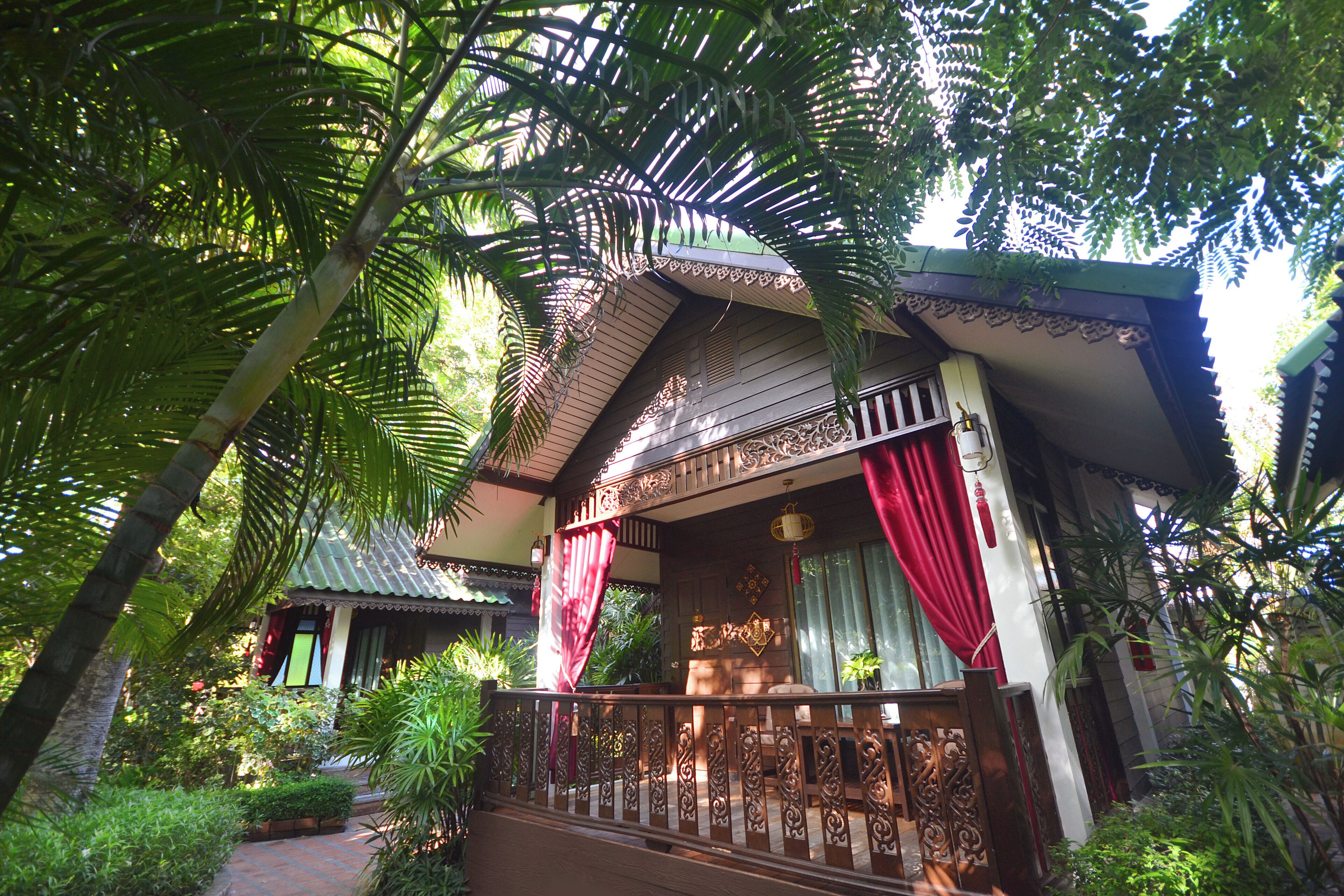 A traditional wooden building with a balcony, surrounded by lush greenery.