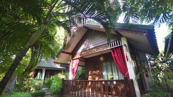 A traditional wooden building with a balcony, surrounded by lush greenery.