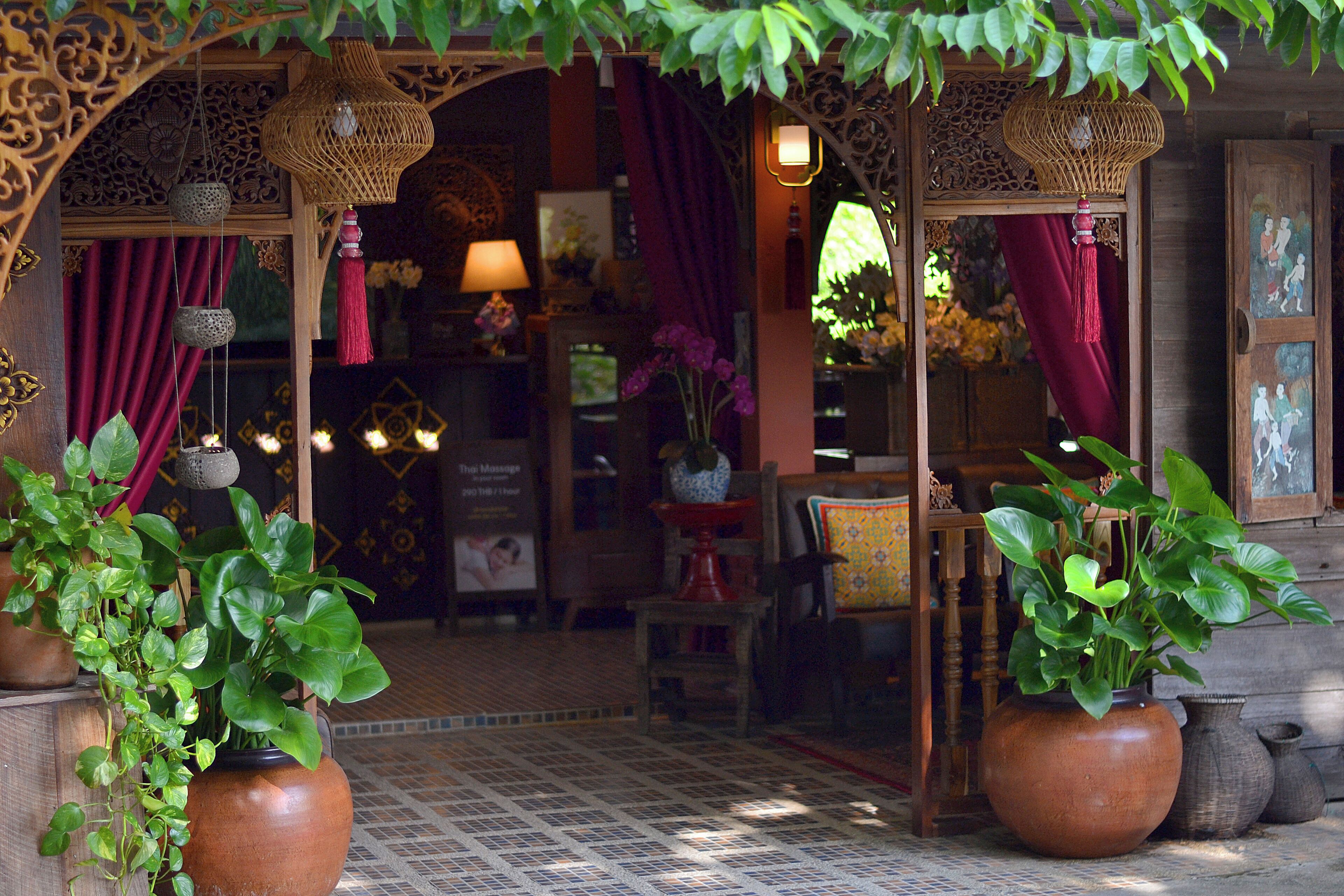 Un intérieur traditionnel avec une arche en bois, des plantes en pot et un sol carrelé.