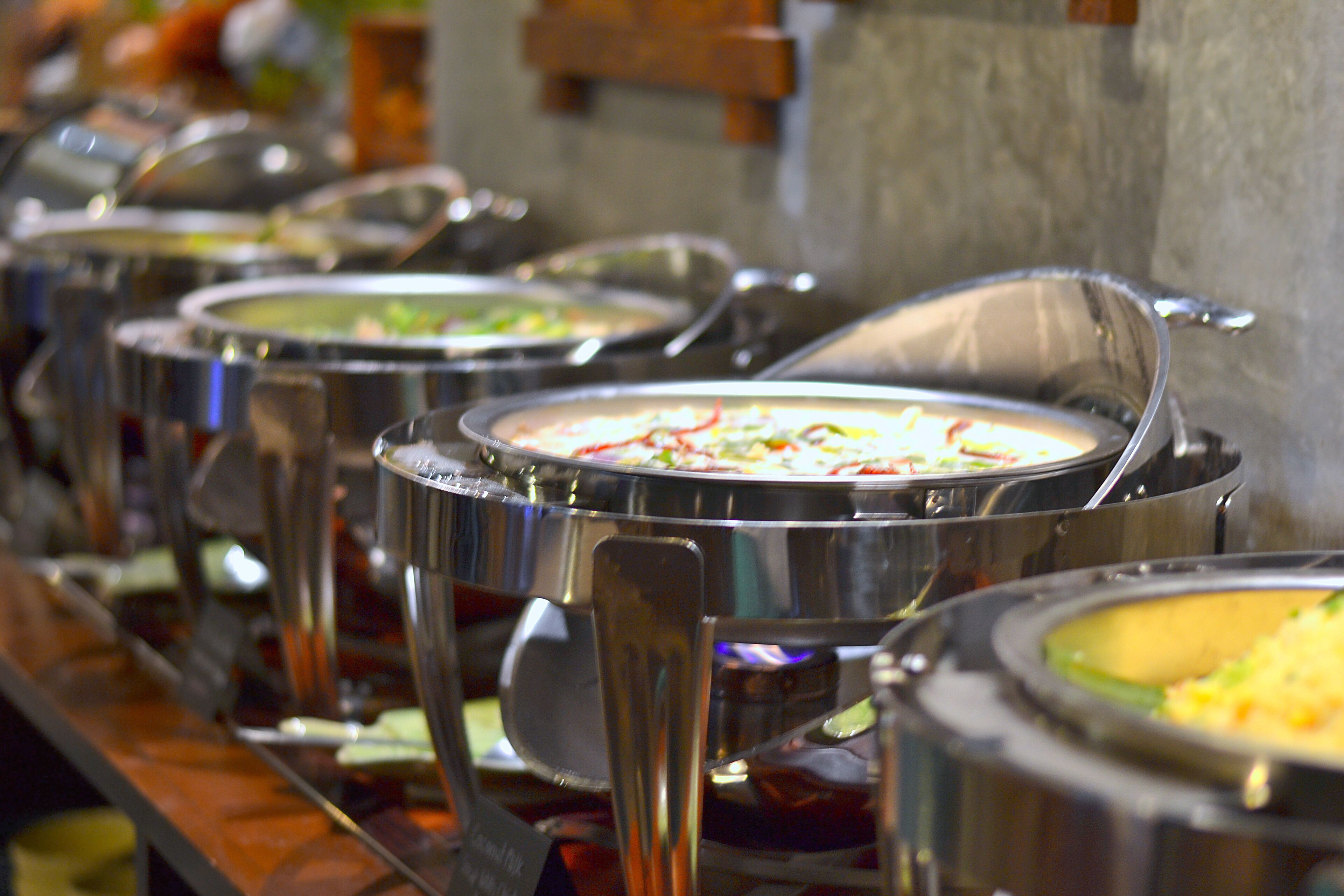 A buffet line with various dishes in metal serving containers.