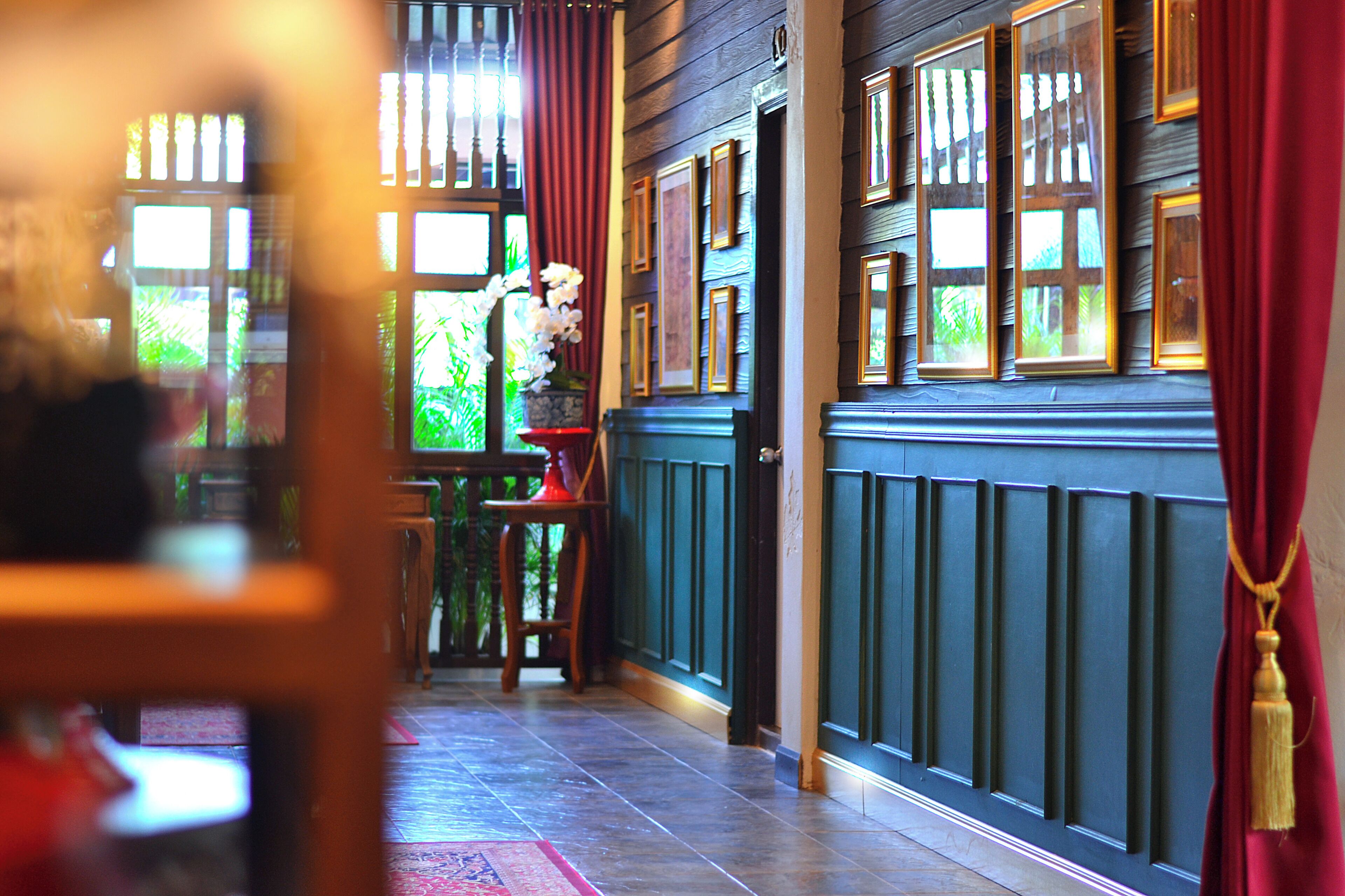 A hallway with wooden paneling, framed pictures, and a red curtain.
